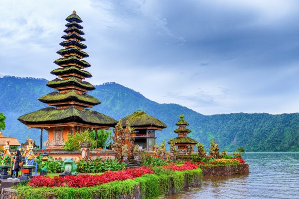 An idyllic temple with a tiered roof sits on the shores of a lake.