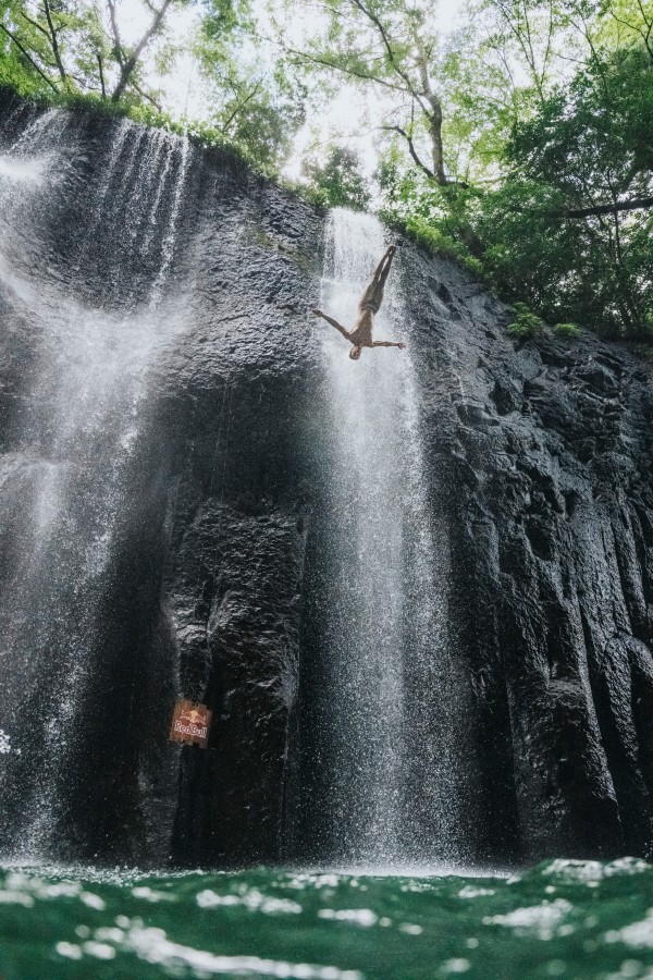 A man leaps from the side of a gorge and into the water.